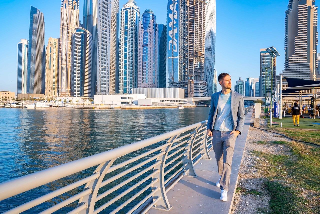 Young man walking at the promenade in Dubai Marina. Handsome businessman standing at Dubai Marina thinking about the business ideas.