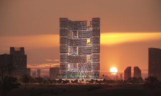 башня Binghatti Hills на фоне закатного неба с освещенными террасами